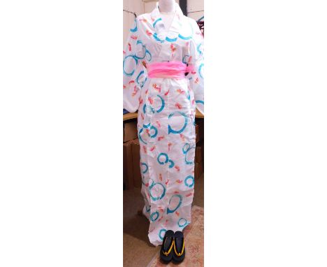 A modern cotton kimono, in white with printed pink fish and blue circles, with obi style sash and traditional styled sandals