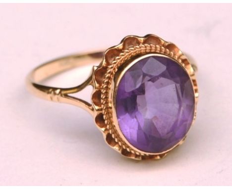 A 9ct gold and amethyst ring, the large central oval cut amethyst within frilly gold bezel setting, stamped 375, ring size Q