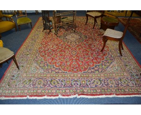 A large Persian carpet, with central blue motif over red ground, with allover multicoloured foliate decoration, 395cm x 290cm