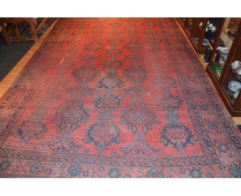 A large Eastern carpet, with central blue foliate diamonds over red ground, with floral border, 615 x 406cm (areas worn) COND