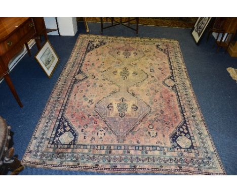 An Eastern carpet, with green, navy and beige triple diamond to centre on pink ground, with triple border, 298cm x 206cm