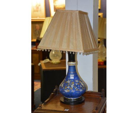 An opaque glass vase/lamp with shade, decorated with floral panels on blue ground, raised on circular base, 38cm high