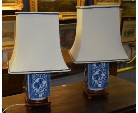 A pair of Oriental blue and white vase lamps, with cream shades, decorated with Chinese dragons and flower motifs, on hardwoo