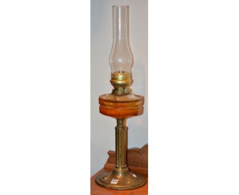 A late Victorian brass oil lamp, with glass funnel and amber coloured glass reservoir, impressed stylized leaf decoration to 