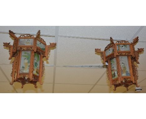 A pair of Oriental lantern lights, the pierced foliate wooden frames set with glass panels painted with geishas in landscape,