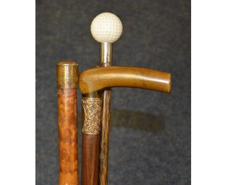 Three walking sticks, one with horn handle and rolled gold collar, one enclosing a yard stick, the third with golf ball pomme