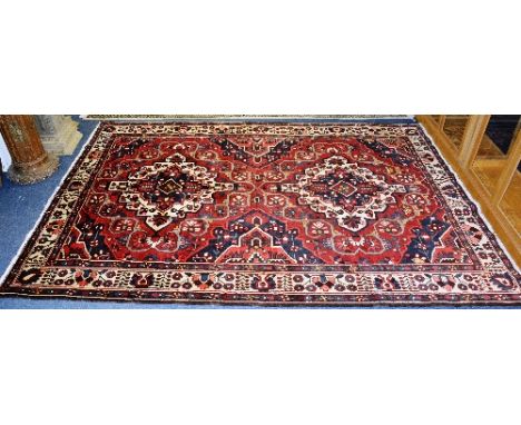 A Bakhtiar carpet, with double cream and navy diamond to centre on red ground, with allover foliate design and cream border, 