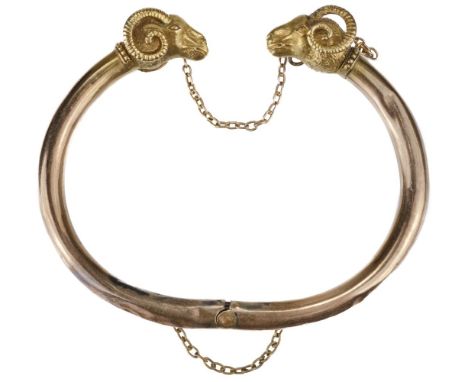 * Bangle. An Indian yellow metal bangle, the hollow rose coloured bangle with yellow metal ram head terminals each with a bea