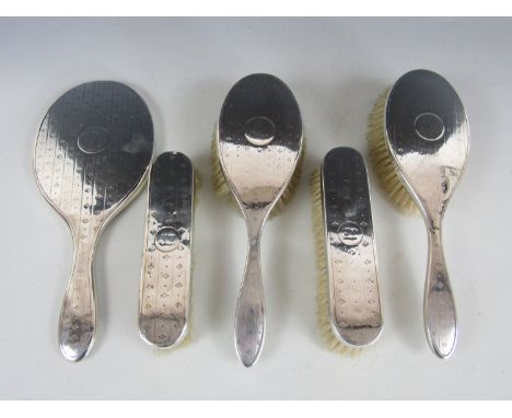 An early George V silver brush set, comprising hand mirror, a pair of hair brushes and a pair of clothes brushes, each having