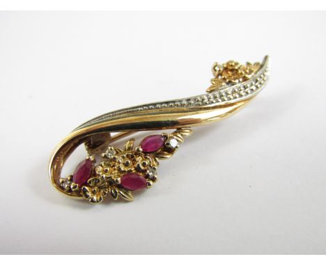 A ruby, diamond and two-colour 9ct gold brooch, modelled as a floral-sprig-adorned scroll, 4 cm