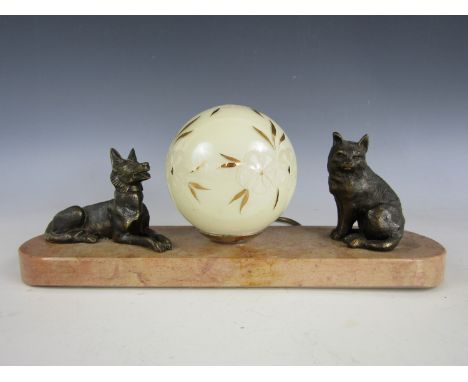 An Art Deco figural table lamp, with a central spherical glass shade decorated with flowers, flanked by a bronzed cat and dog