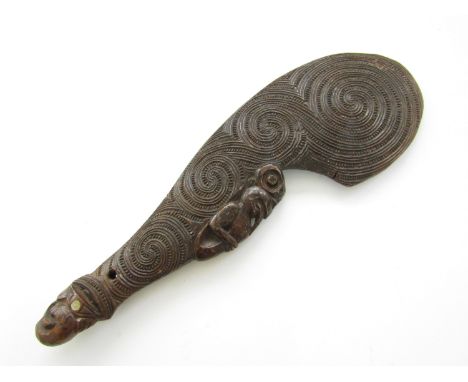 A 19th Century Maori carved wooden wahaika, decorated in a reed and bead spiral pattern and faced with a depiction of a tiki 