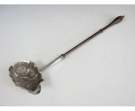 A George II white-metal punch ladle, the oval shaped bowl being lobed and repousse moulded in depiction of flowers and foliag