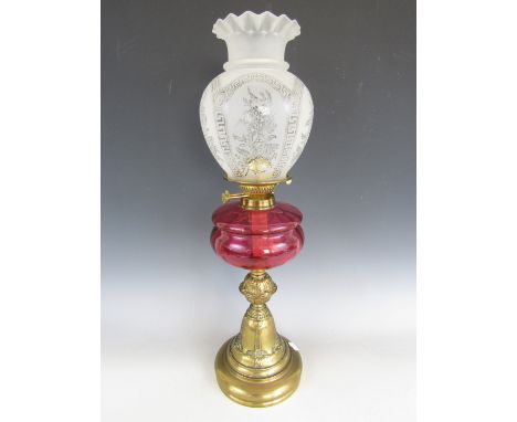A late 19th / early 20th Century oil lamp, with etched glass shade, cranberry glass reservoir and moulded knopped base bearin