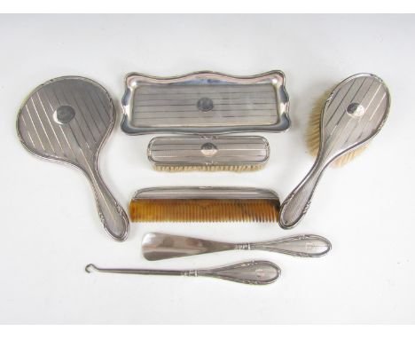 An extensive George V silver dressing table set comprising tray, shoe horn and button hook, comb, brush and mirror, each deco