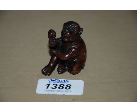 A finely carved and signed Fruitwood Netsuke of a monkey with signed Mother of Pearl cartouche to the base.