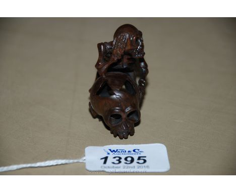 An unusual signed Fruitwood Netsuke in the form of a skeleton holding a skull.