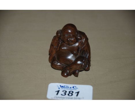 A signed carved Japanese fruit wood Netsuke of a seated figure of the happy Buddha 'Hotei', with inlaid signed Mother of Pear