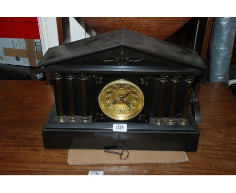 A Black Slate Mantle Clock with three Corinthian columns either side, gold coloured face and black numbering