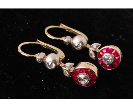 A pair of late 19th century ruby and diamond drop earrings. The earrings having a central diamond within a calibrated ruby su