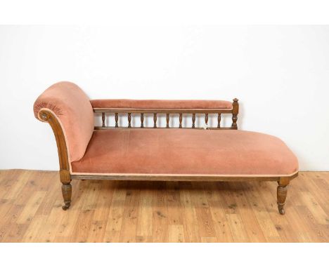 A Victorian chaise longue, the oak frame with galleried arm rest, upholstered in pink velvet fabric, raised on turned feet an