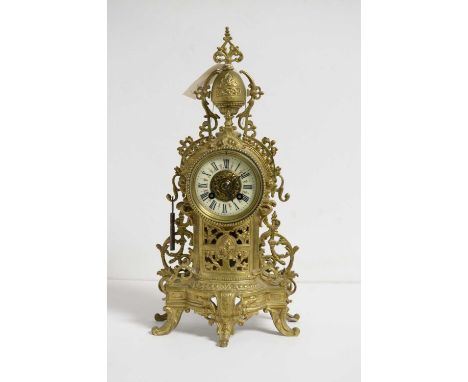 A late 19th / early 20th Century French ormolu brass mantel clock, with Roman numerals and an enamelled chapter, in an ornate