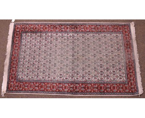 A 20th Century Indian Moud rug, the central panel with a repeating geometric pattern, set within a polychrome border, 125 x 2