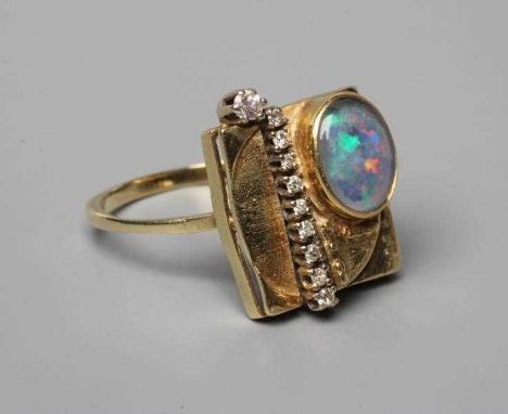 A SECESSIONIST STYLE COCKTAIL RING, the square panel close back collet set with an oval cabochon polished opal offset to one 