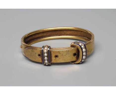 A VICTORIAN STIFF HINGED BUCKLE BANGLE, the upper section with two seed pearl and blue enamel "straps" and three pierced hole