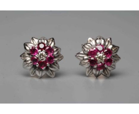A PAIR OF RUBY AND DIAMOND CLUSTER EAR STUDS, the flowerheads centred by a small diamond to a border of six small facet cut r