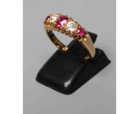 A LATE VICTORIAN RUBY AND DIAMOND RING, the oval facet cut central ruby flanked by two old brilliant cut diamonds and two fur