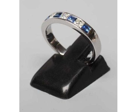 A SAPPHIRE AND DIAMOND HALF HOOP ETERNITY RING, the four sapphires and three princess cut diamonds channel set to a plain 18c