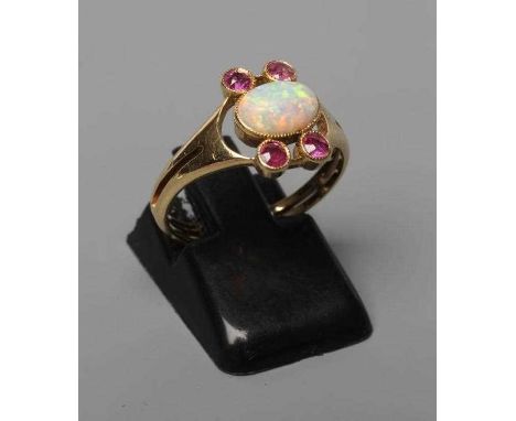 A MURRLE BENNETT DRESS RING, the oval cabochon polished opal collet set with two pairs of small rubies to an open frame and s