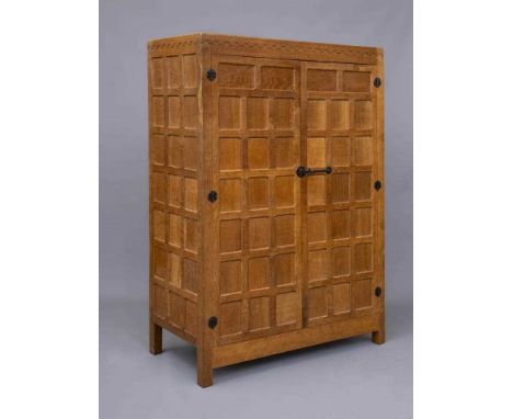 A ROBERT THOMPSON ADZED OAK WARDROBE of oblong multi panelled form with half penny moulded cornice, two doors with wrought ir