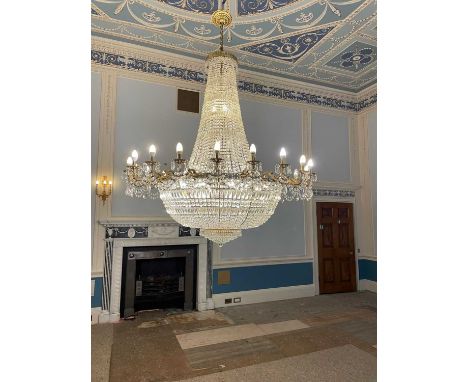 A GILT METAL AND CUT GLASS TWENTY FLAME CHANDELIER, 20th century, of tent form with crystal drops, the scroll branches issuin