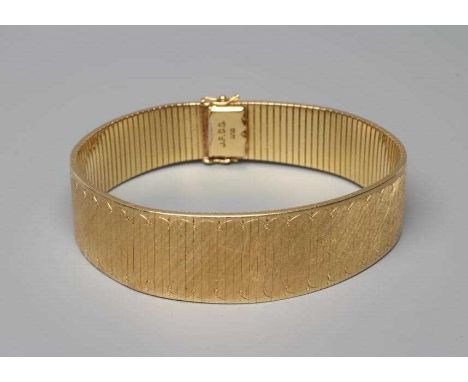 AN ARTICULATED BRACELET, the finely engine turned oblong links with a swag engraved border and slide fastener, stamped 750, J