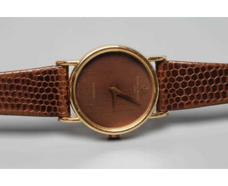 A LADY'S 18CT GOLD BAUME &amp; MERCIER WRISTWATCH, the brown grained plain dial with gilt metal hands and logo, thirty jewel 