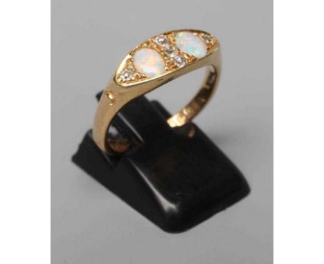 AN EDWARDIAN OPAL AND DIAMOND RING, the eliptical panel set with two oval cabochon polished opals and five point set small di