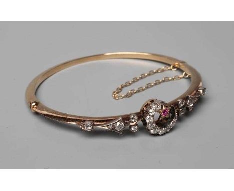 A VICTORIAN STIFF HINGED BANGLE, the upper section centred by a diamond set crescent moon and ruby star, the shoulders each s