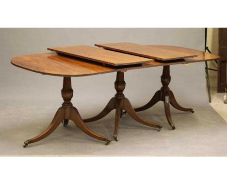 A MAHOGANY EXTENDING THREE PILLAR DINING TABLE of Georgian design, late 19th century, the reeded edged top with two leaves, r