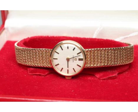 A LADY'S 9CT GOLD OMEGA WRISTWATCH, the pale champagne dial with applied gilt metal batons, in a plain case on integral chain