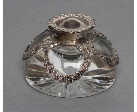 AN EDWARDIAN SILVER MOUNTED HEAVY CLEAR GLASS DOMED INKWELL with star cut base, the mount with cast and pierced ribbon tied s