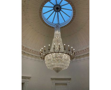 AN IMPRESSIVE GILT METAL AND CUT GLASS TWENTY FOUR FLAME CHANDELIER, 20th century, of tent form with crystal drops, the scrol