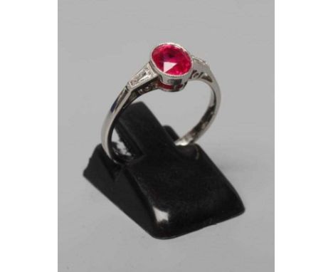 A RUBY RING, the oval facet cut stone of 1.27cts, collet set to shaped shoulders each set with a tapering baguette cut diamon