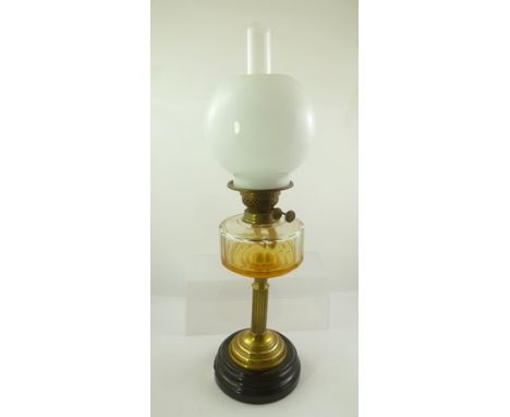 A LATE VICTORIAN OIL LAMP having fluted brass column supporting a clear glass reservoir and opaque globe shade, with chimney 