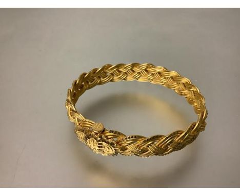 A striking 22ct gold bangle, hinged, of intricate polished and textured woven design, the pin clasp stamped "22" and "916" an