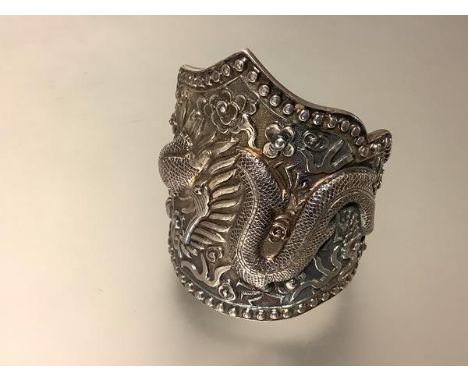 A substantial Chinese silver cuff bangle, chased in high relief with a dragon and flaming pearls, stamped "China", "Silver" t