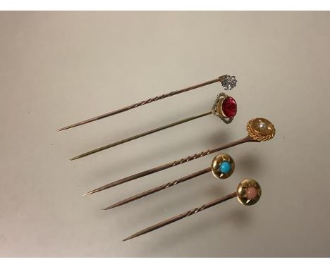 A group of five stick pins, early 20th century, one set with a seed pearl, the pin stamped "10", the second with a red stone 