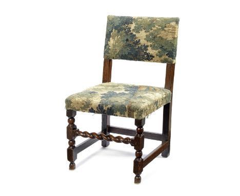 A 17th century oak chairUpholstered in a Verdure tapestry fragment, on turned and block carved front legs united by a spiral 