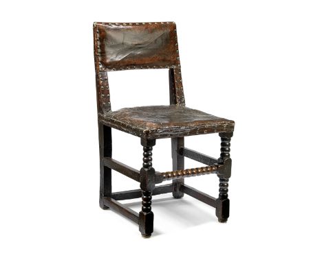 A mid-17th century oak and leather upholstered chairWith bobbin-turned front legs joined by a bobbin twist stretcher, 48cm wi